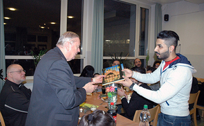 Joan Ali, Asylwerber aus Syrien, hat in der Pfarre Linz-St. Peter ein sicheres Zuhause gefunden. Er bedankt sich bei Bischof Ludwig Schwarz mit einem Syrien-Bildband für die Unterstützung.